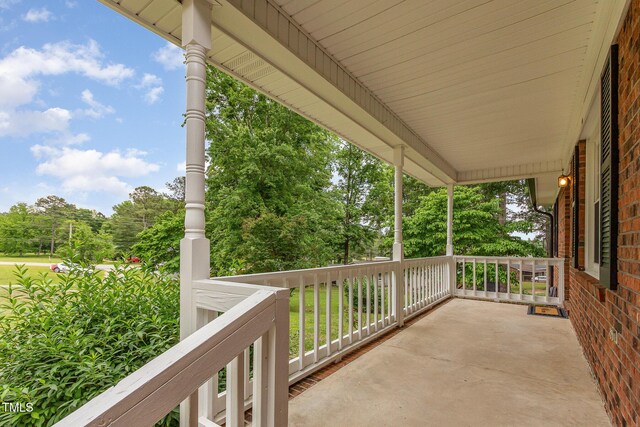 balcony featuring covered porch and view of wooded area