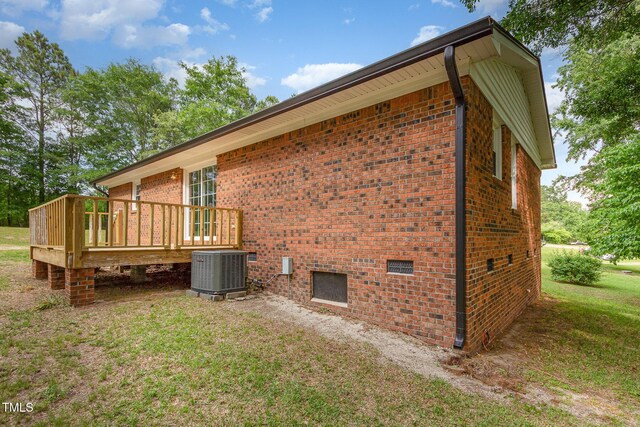 view of home's exterior featuring central air condition unit, a deck, brick siding, and a yard