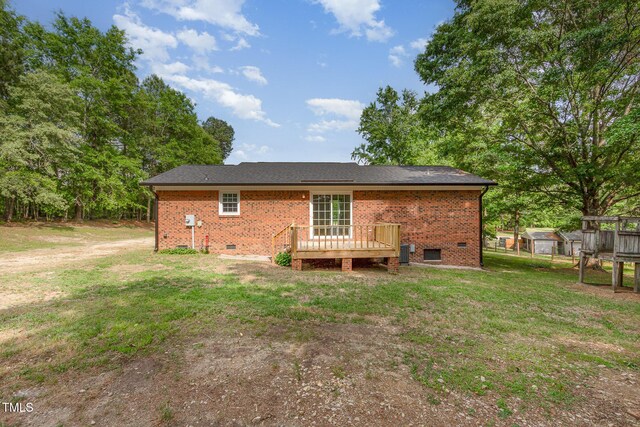 back of property with crawl space, brick siding, a wooden deck, and a yard