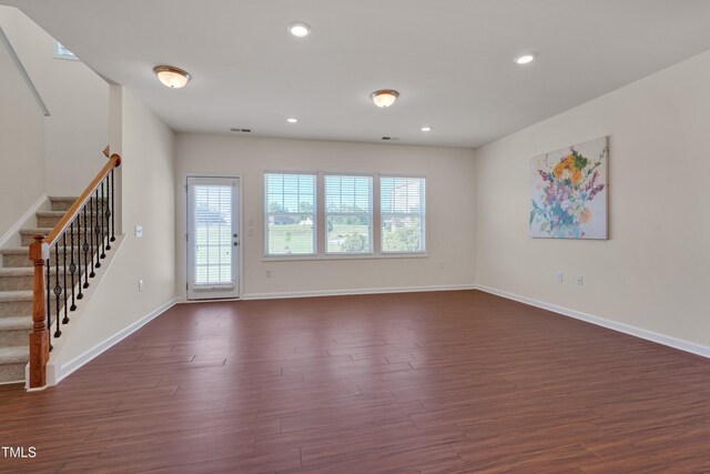 unfurnished living room with dark wood-style floors, stairway, baseboards, and recessed lighting