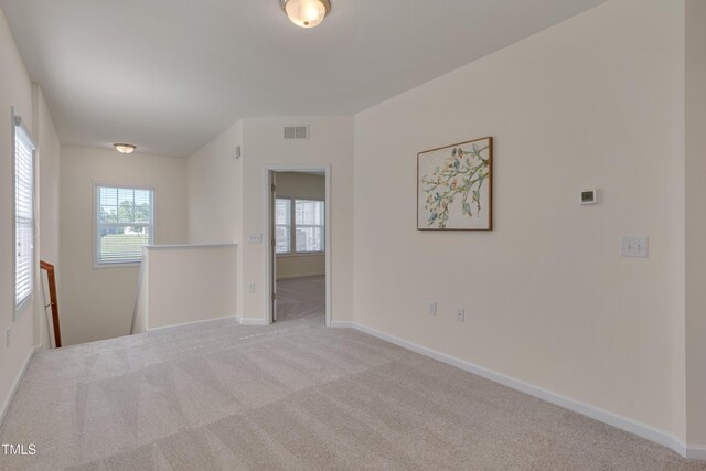 unfurnished room with healthy amount of natural light, baseboards, and carpet