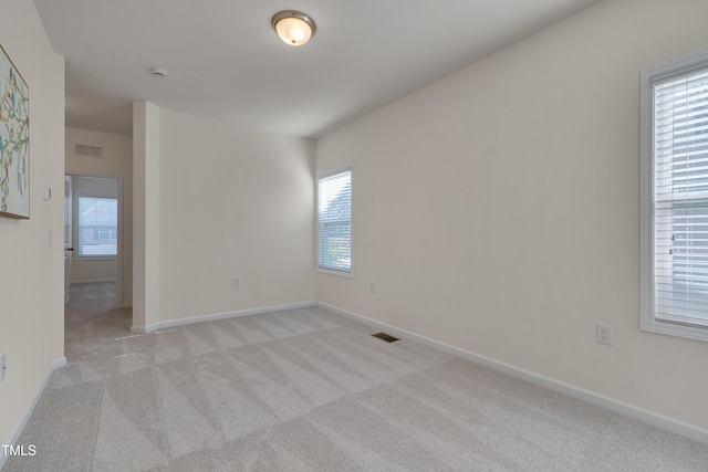spare room with light carpet, baseboards, and a smoke detector