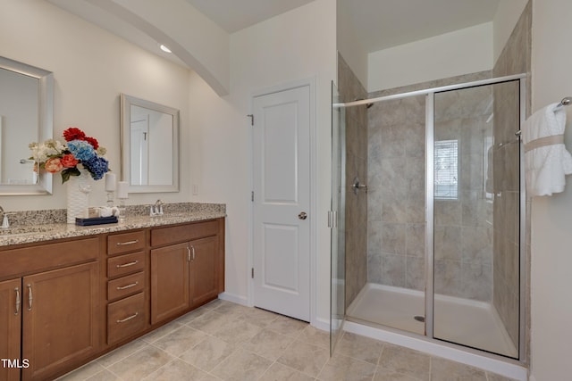 full bathroom with a stall shower, double vanity, and tile patterned flooring