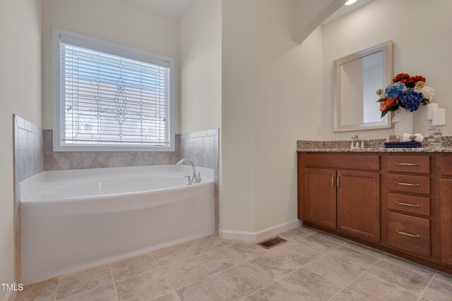 bathroom with a garden tub, vanity, tile patterned flooring, and baseboards