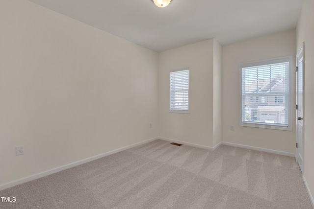 spare room featuring light carpet and baseboards