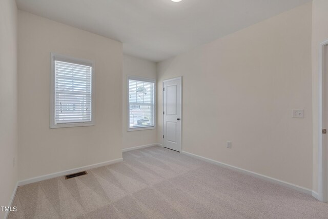unfurnished room featuring light colored carpet and baseboards