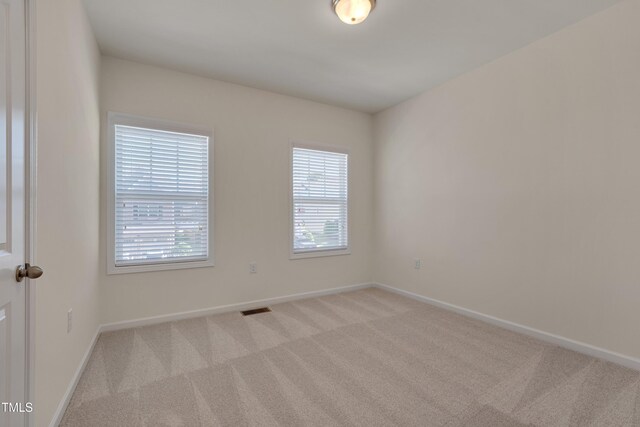 carpeted spare room featuring healthy amount of natural light and baseboards