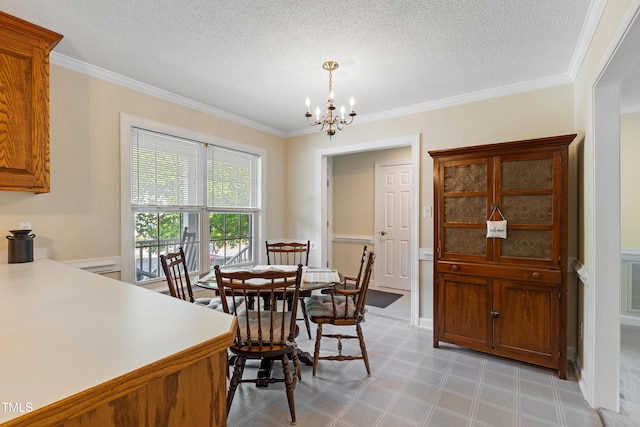 dining space featuring a chandelier, crown molding, light flooring, a textured ceiling, and wainscoting