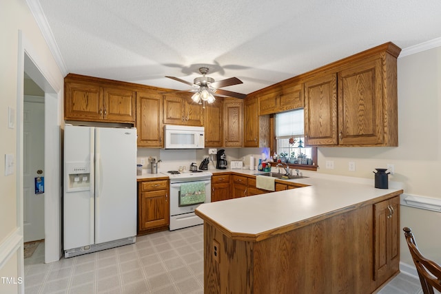 kitchen featuring white appliances, brown cabinetry, a peninsula, a sink, and ornamental molding