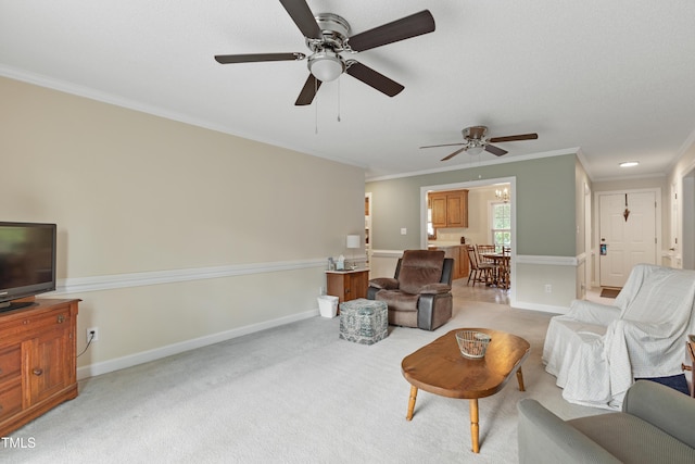 living room with ceiling fan, ornamental molding, baseboards, and light carpet