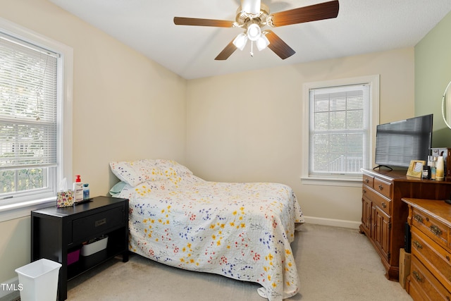 bedroom with light colored carpet, baseboards, and ceiling fan