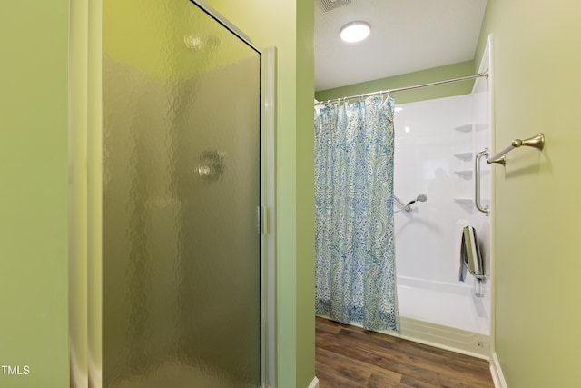 bathroom with a shower stall and wood finished floors