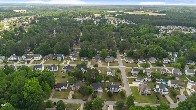 aerial view of property and surrounding area with a heavily wooded area and nearby suburban area
