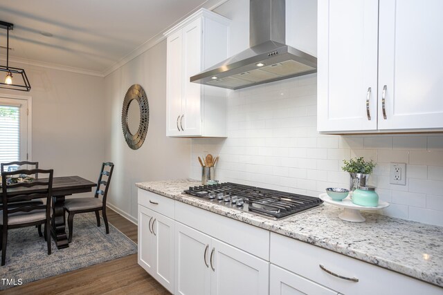1048 Flagler St, Durham, NC 27713 - kitchen with wall chimney exhaust hood, stainless steel gas stovetop, wood finished floors, white cabinets, and tasteful backsplash