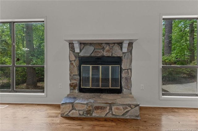 detailed view of wood finished floors, baseboards, and a stone fireplace