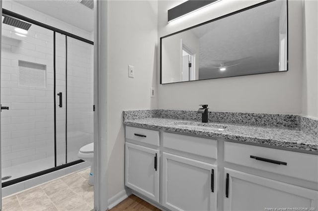 bathroom featuring a shower stall, toilet, and vanity