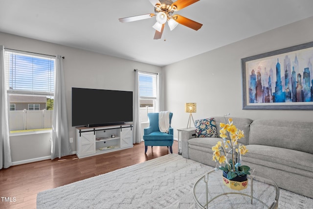 living area with wood finished floors, a ceiling fan, and baseboards