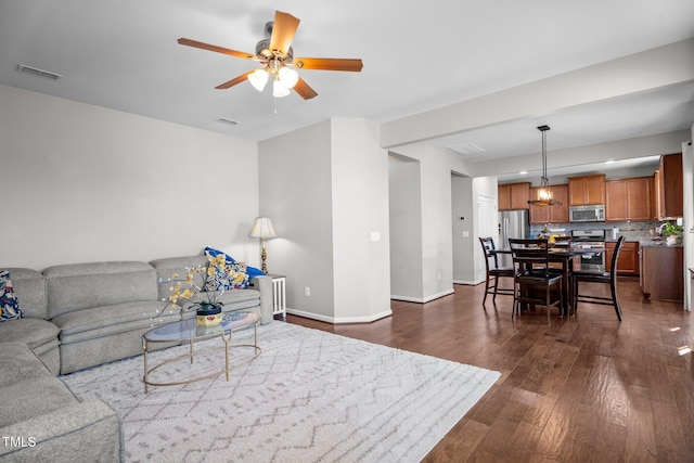 living area with dark wood-style flooring, ceiling fan, and baseboards