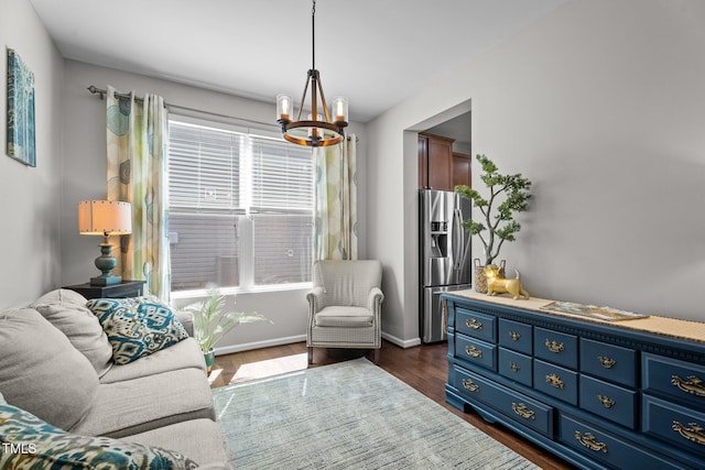 living area featuring a chandelier, dark wood finished floors, and baseboards