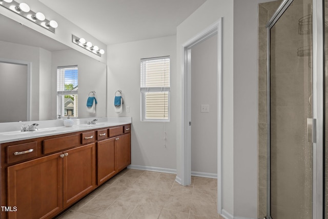 full bath featuring tiled shower, double vanity, tile patterned floors, and baseboards