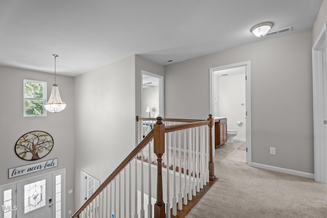 hall featuring an upstairs landing, baseboards, light colored carpet, and a chandelier