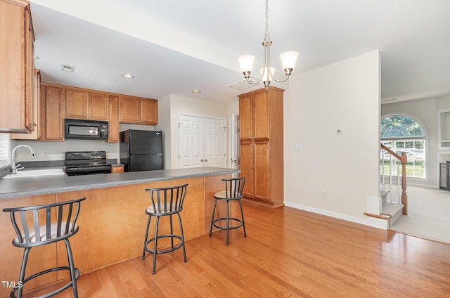 2111 Piney Brook Rd Unit 101, Raleigh, NC 27614 - kitchen featuring black appliances, a peninsula, light wood-style floors, a chandelier, and recessed lighting