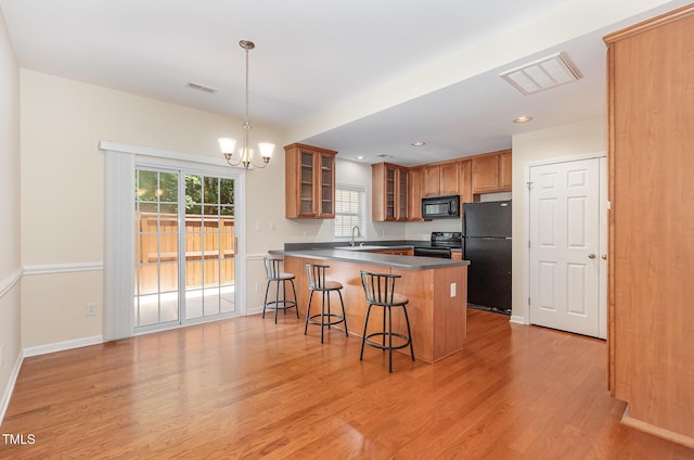 2111 Piney Brook Rd Unit 101, Raleigh, NC 27614 - kitchen featuring black appliances, a peninsula, light wood-type flooring, a chandelier, and glass insert cabinets