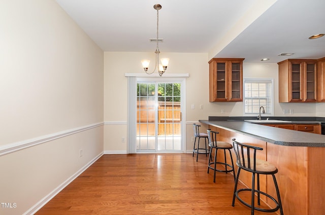 2111 Piney Brook Rd Unit 101, Raleigh, NC 27614 - kitchen featuring dark countertops, brown cabinets, a breakfast bar area, light wood-style flooring, and recessed lighting
