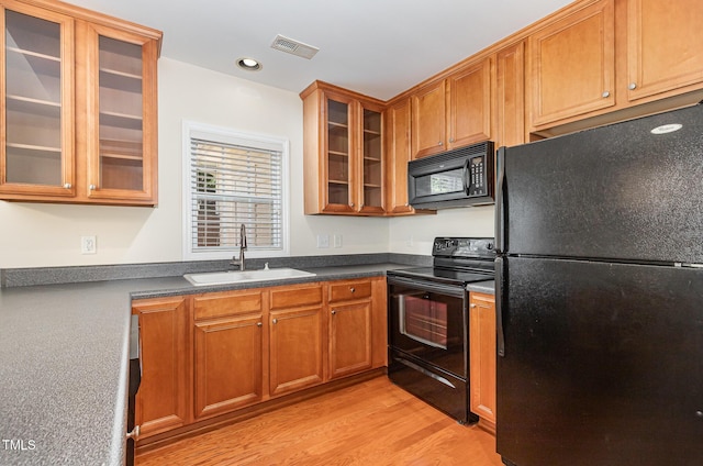 2111 Piney Brook Rd Unit 101, Raleigh, NC 27614 - kitchen with black appliances, light wood-type flooring, brown cabinets, glass insert cabinets, and dark countertops
