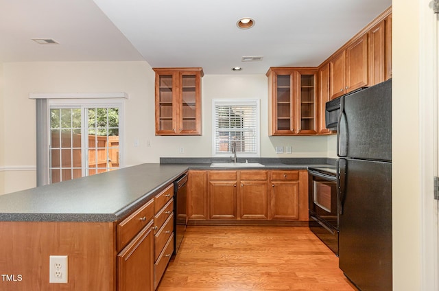 2111 Piney Brook Rd Unit 101, Raleigh, NC 27614 - kitchen with black appliances, a peninsula, dark countertops, brown cabinetry, and healthy amount of natural light