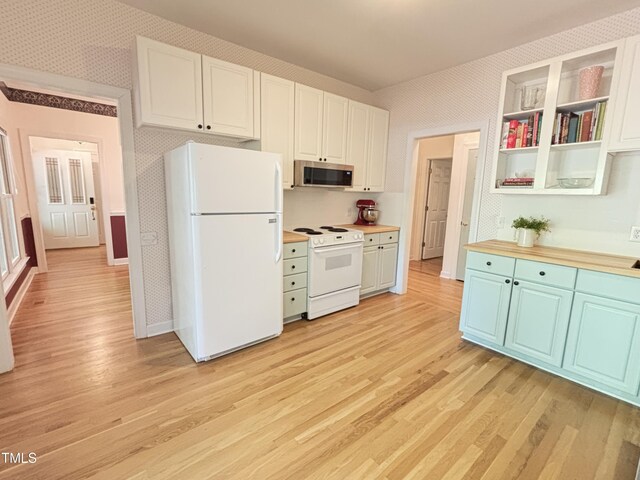 kitchen with white appliances, wallpapered walls, light wood-style flooring, and white cabinets