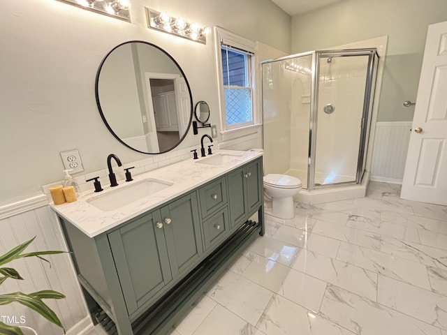 bathroom with wainscoting, marble finish flooring, a shower stall, double vanity, and toilet