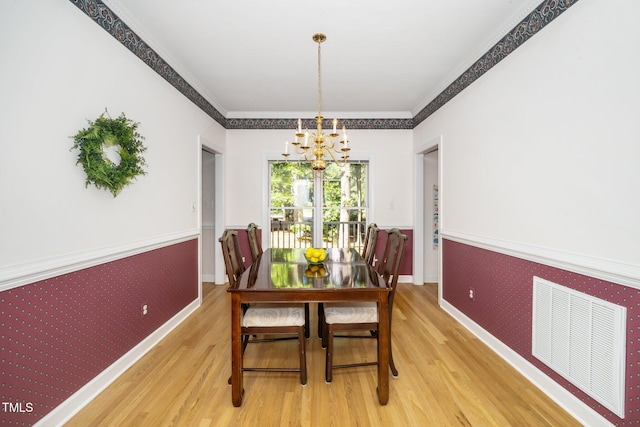 dining space featuring a chandelier, wood finished floors, wallpapered walls, baseboards, and a wainscoted wall