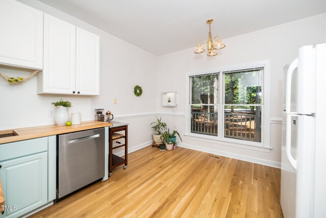 kitchen with dishwasher, freestanding refrigerator, a chandelier, light wood finished floors, and wainscoting