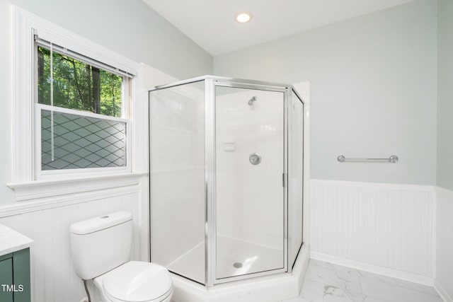 bathroom with wainscoting, a shower stall, marble finish flooring, vanity, and toilet
