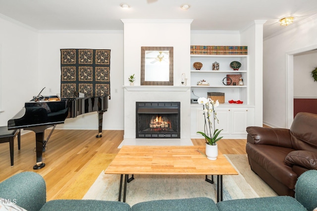 living area with crown molding, wood finished floors, and a fireplace with flush hearth