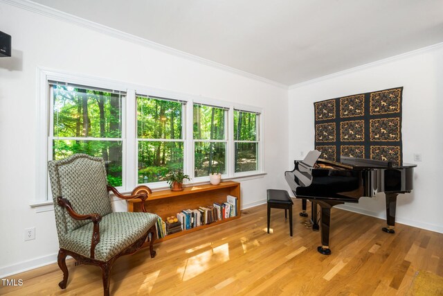 sitting room with plenty of natural light, crown molding, wood finished floors, and baseboards
