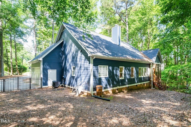rear view of property with a chimney, stairs, fence, and roof with shingles