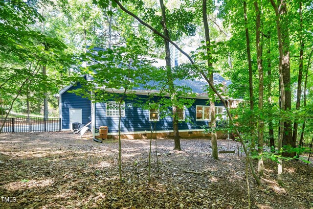 rear view of property with crawl space, fence, a shingled roof, and a chimney
