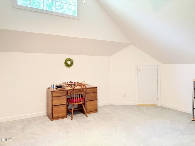 office area with vaulted ceiling, light carpet, and baseboards