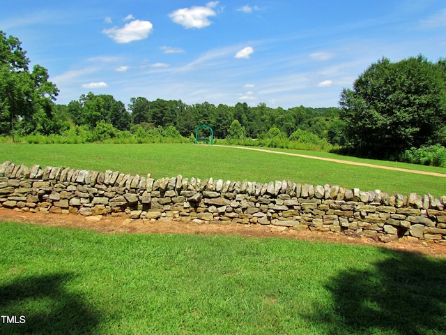 view of grassy yard featuring a forest view