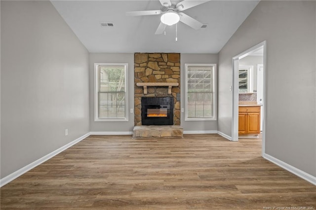 unfurnished living room featuring lofted ceiling, wood finished floors, baseboards, a fireplace, and ceiling fan