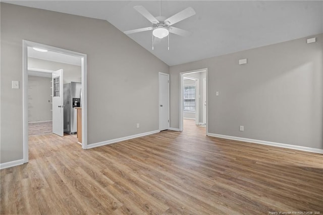 empty room featuring ceiling fan, vaulted ceiling, light wood-style floors, and baseboards
