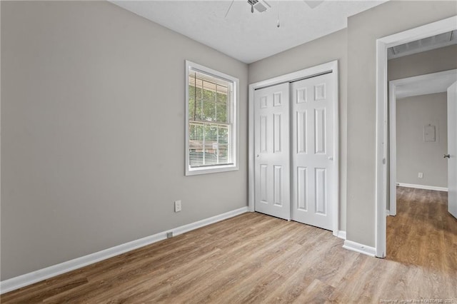 unfurnished bedroom featuring wood finished floors, baseboards, a closet, and ceiling fan
