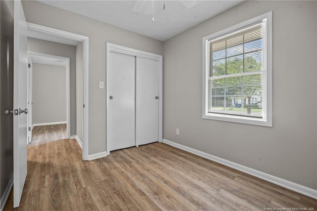 unfurnished bedroom with wood finished floors, baseboards, a closet, and ceiling fan