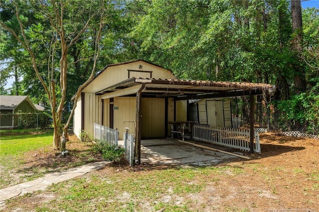 view of outdoor structure featuring an outbuilding, fence, and a detached carport