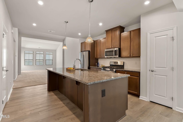 1745 Ripley Woods St, Wake Forest, NC 27587 - kitchen featuring appliances with stainless steel finishes, a center island with sink, stone counters, recessed lighting, and brown cabinets