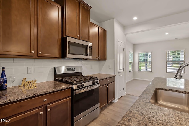 1745 Ripley Woods St, Wake Forest, NC 27587 - kitchen with appliances with stainless steel finishes, backsplash, dark stone counters, light wood-style flooring, and recessed lighting