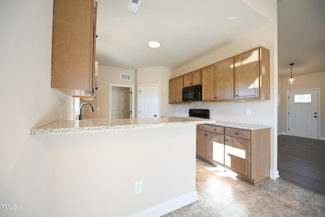kitchen featuring black microwave, a peninsula, baseboards, light stone counters, and a sink
