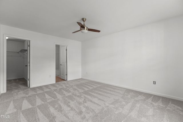 unfurnished bedroom featuring a spacious closet, carpet flooring, baseboards, and a closet